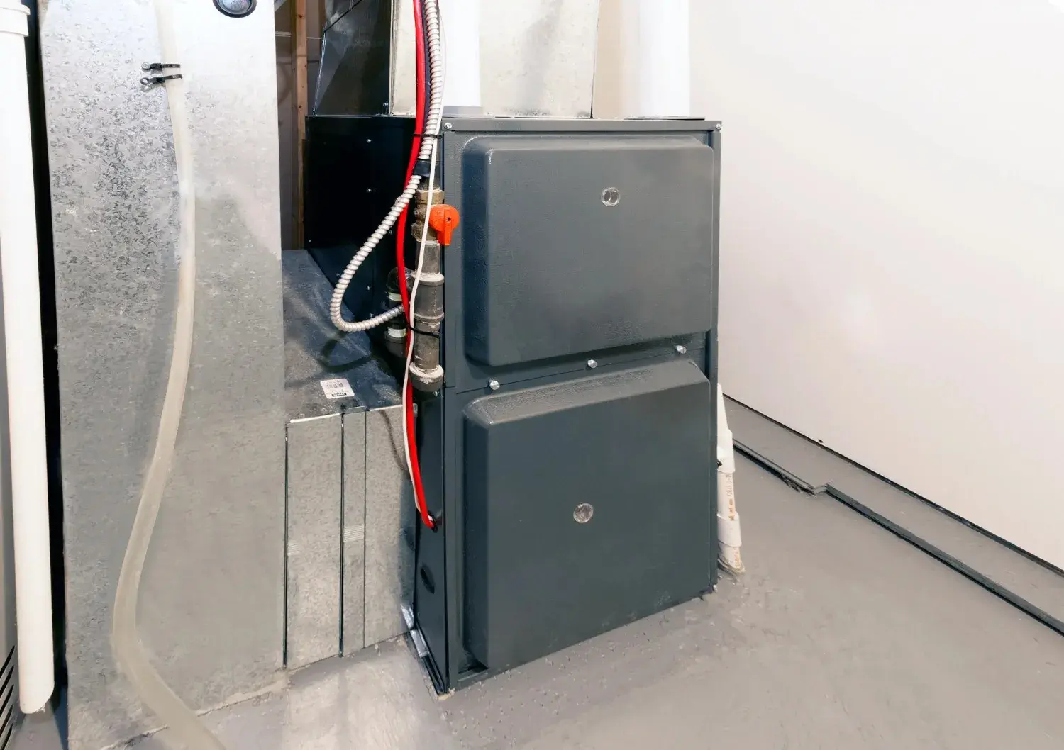 A grey furnace and air handler unit with visible ductwork and piping.